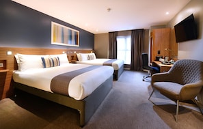 A hotel room with two beds, a desk, a chair, a TV, and a window with curtains. - Travelodge Galway (Galway)