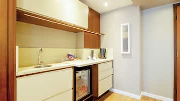 Una cocina compacta con refrigerador integrado, un lavamanos y muebles de madera.