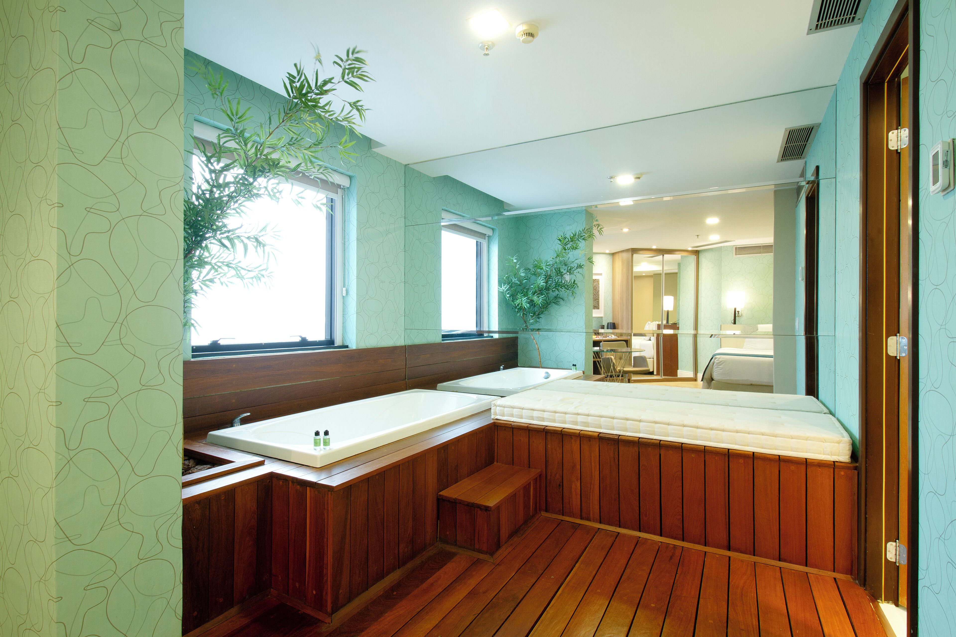 Un baño con un banco de madera, un lavamanos y un espejo.