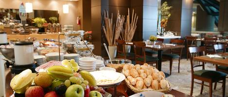A buffet with fruits, pastries, and condiments.