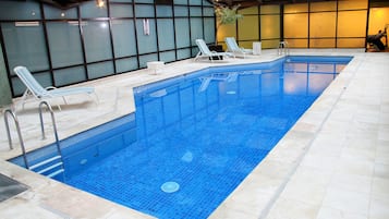 Una piscina techada, sillones reclinables de piscina