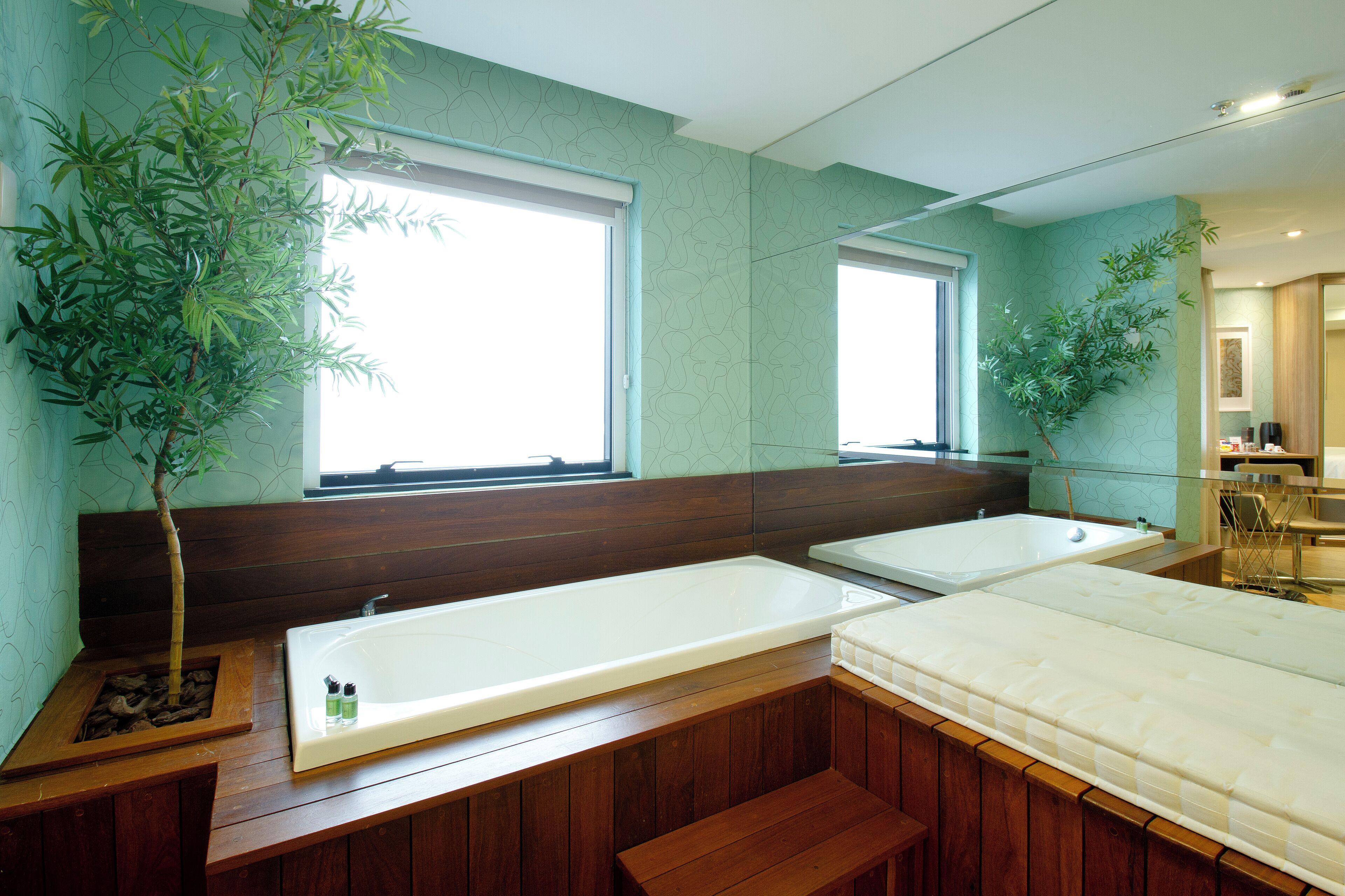 Un baño moderno con dos tinas grandes, bancos de madera y plantas en macetas.