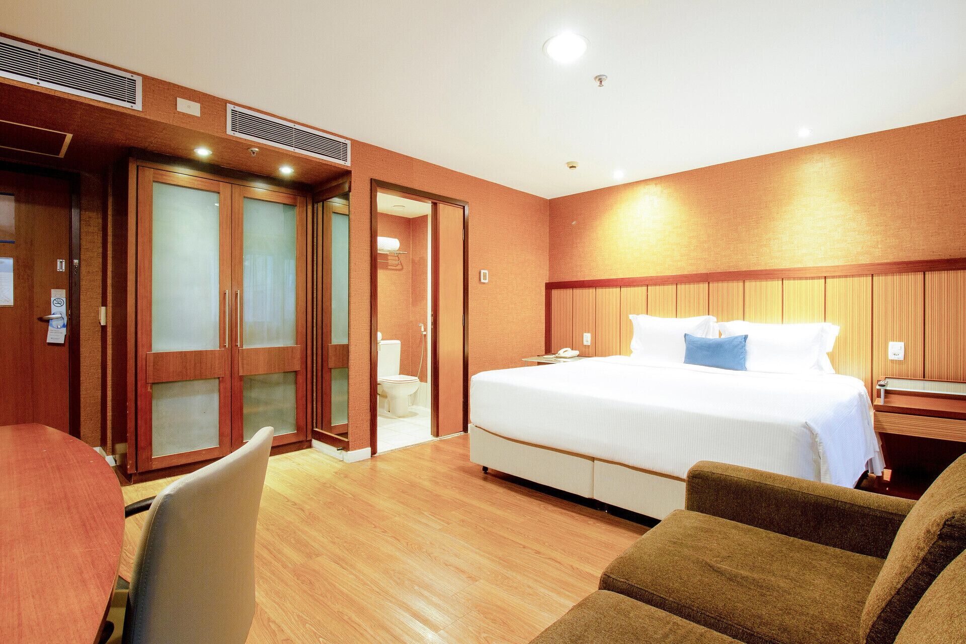 A hotel room with a bed, a desk, a chair, and a bathroom.