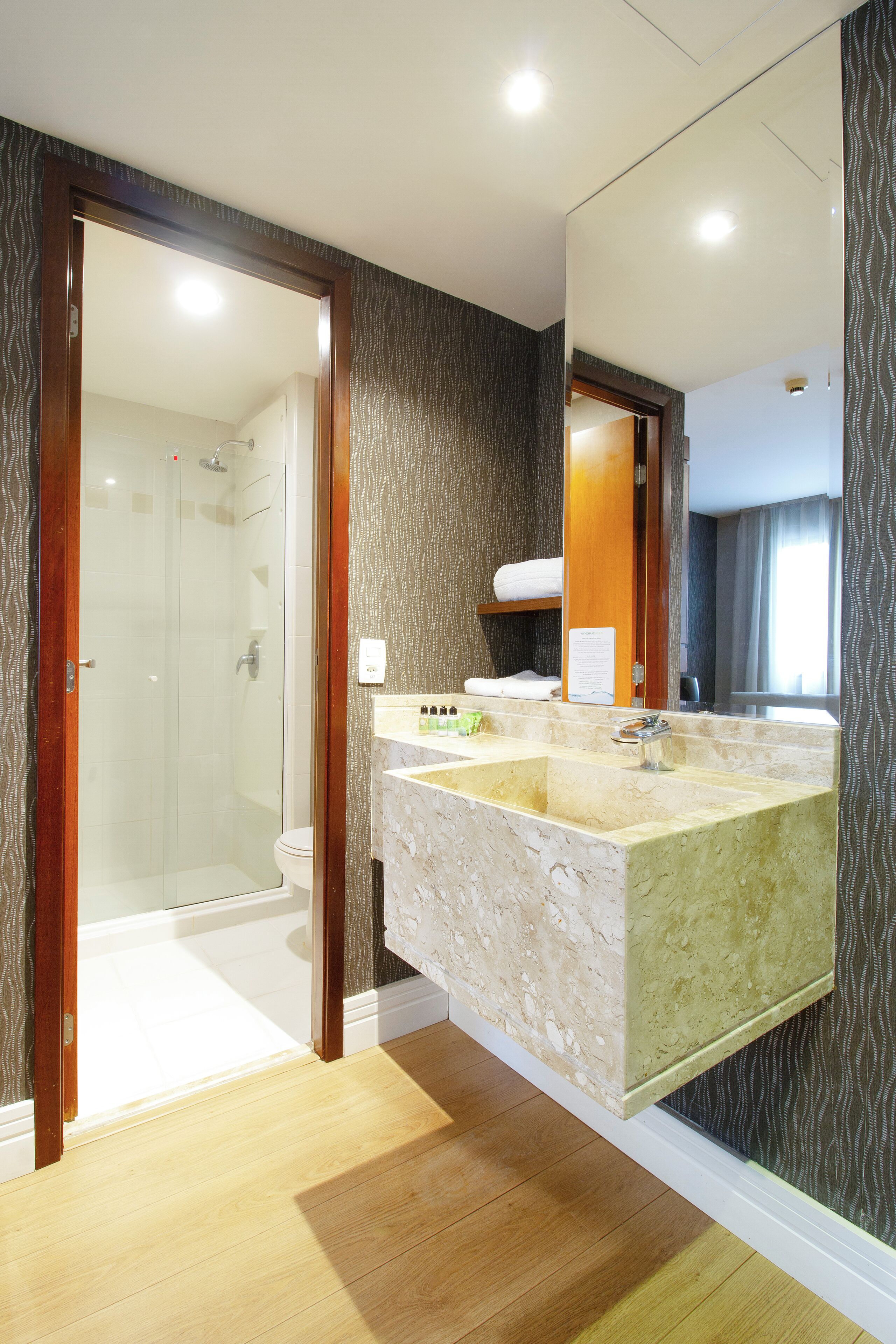 A bathroom with a glass-enclosed shower, a marble sink, and a large mirror.