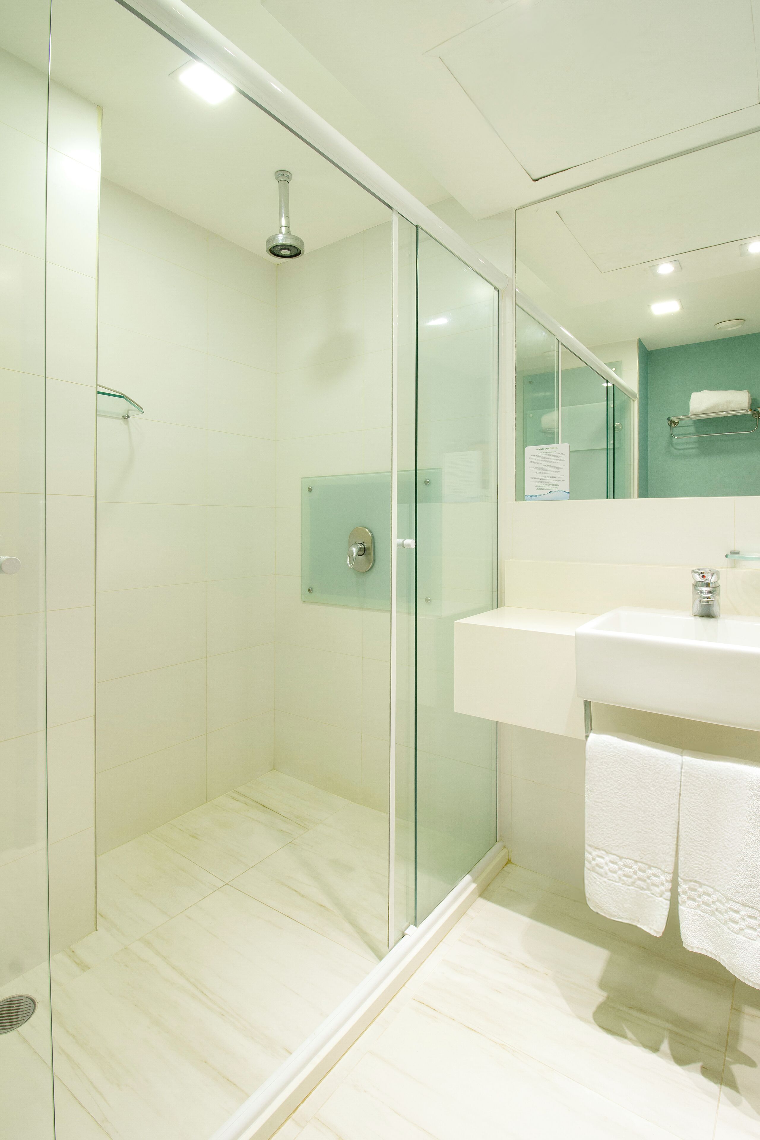Un baño moderno con cabina de ducha de vidrio, un lavamanos blanco y un espejo sobre él.