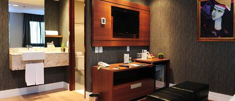A modern bathroom with a vanity, mirror, and a mounted television.