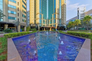 A modern building with a central fountain, surrounded by well-maintained greenery and a clear sky. - Wyndham Sao Paulo Ibirapuera Convention Plaza Hotel (São Paulo)