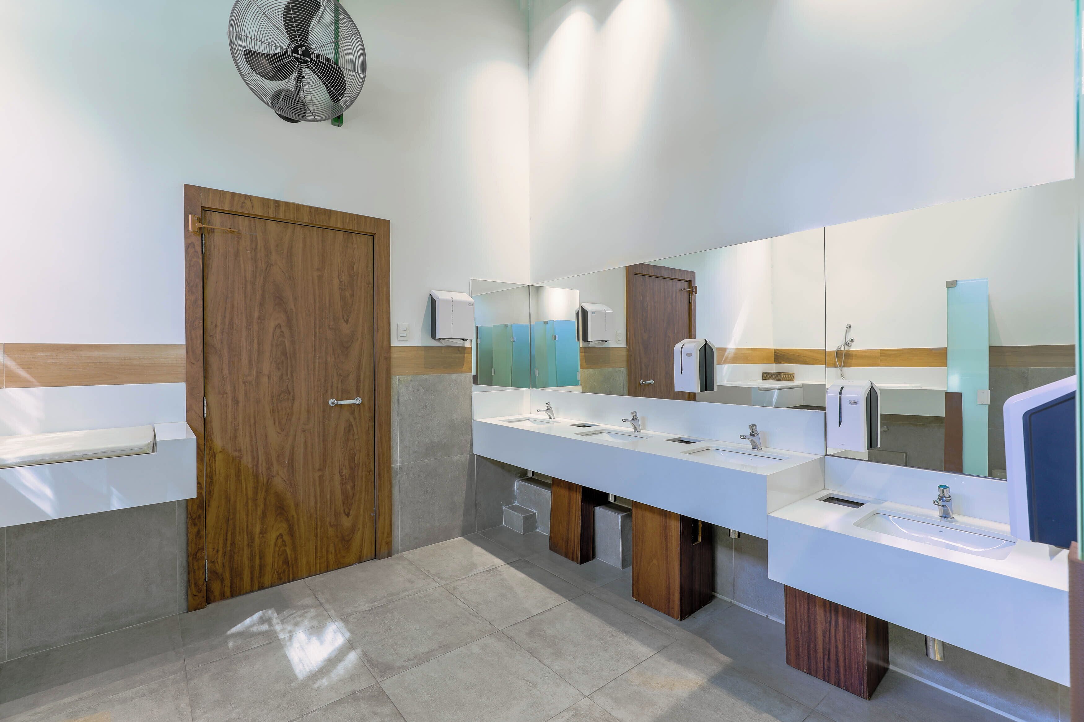 A modern bathroom with two sinks, a wooden door, and a mirror.