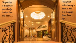 A hotel lobby with a grand staircase, a chandelier, and a seating area.