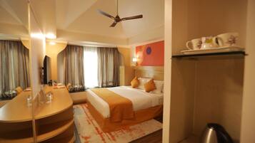 Een hotelkamer met een bed, bureau, spiegel, plafondventilator en een douche.