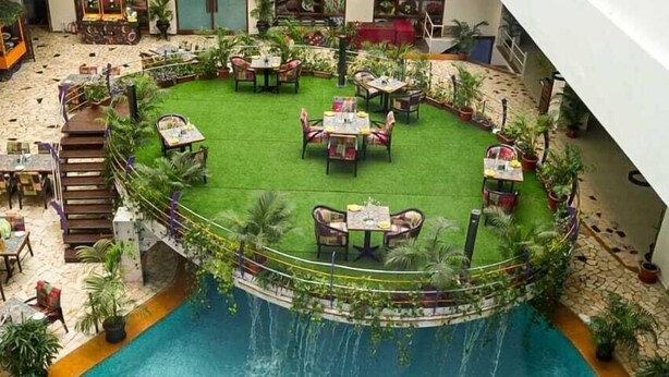 A hotel atrium with a central pool, surrounded by outdoor seating and greenery.