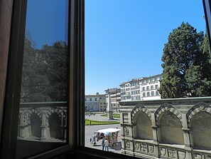 Une vue d’un bâtiment historique doté de fenêtres en arc de cercle, avec un grand arbre devant.