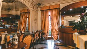 Un interior clàssic amb decoració ornamental al sostre, una zona de bar i un espai de menjador amb cadires i taules.