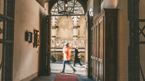Un passadís amb una catifes vermella que condueix a una entrada ampla i d'arc.