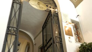 Una entrada en arc amb una reixa de metall, una placa a la paret i una catifa vermella que hi mena.