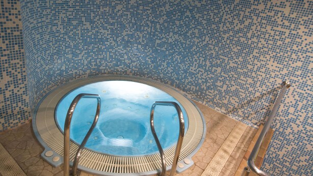 Un jacuzzi con barandillas metálicas y piso de baldosas.