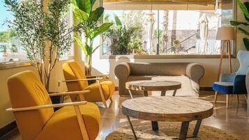 Un área de estar moderna con sillas amarillas, un sofá y una mesa de centro de madera.
