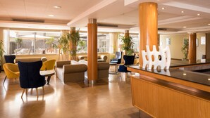 Een moderne lobby met zithoeken, een receptiebalie en grote ramen.