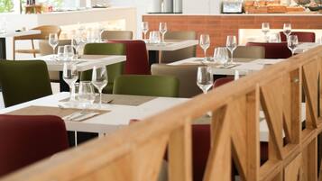 Un restaurante con varias mesas y sillas, cada conjunto con copas de vino y cubiertos.