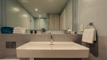 Un baño moderno con un lavamanos grande, un espejo y un perchero para toallas.