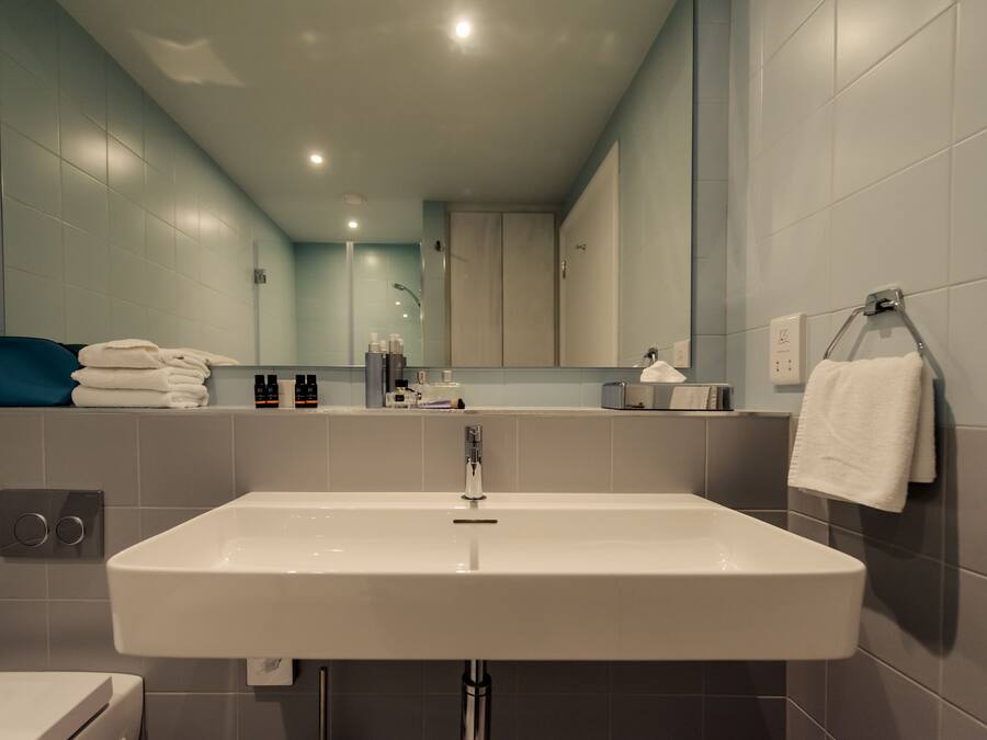 Un baño moderno con un lavamanos grande, un espejo y un perchero para toallas.
