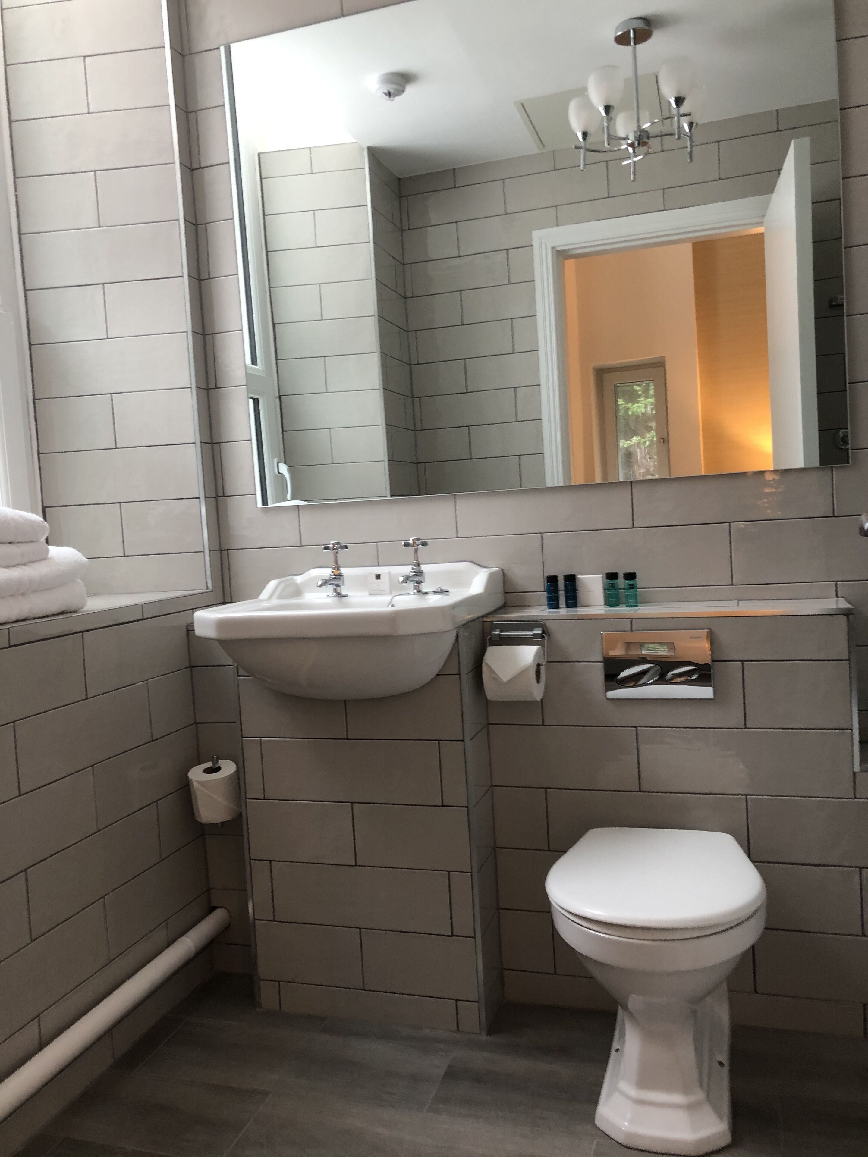 A modern bathroom with a white sink, mirror, and toilet.
