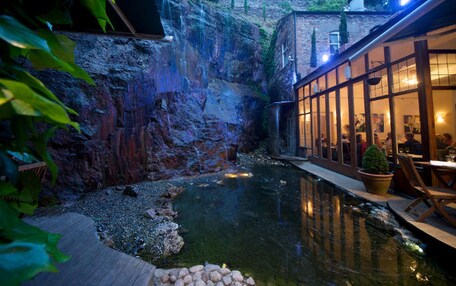 Una tranquila fuente interior con un fondo rocoso y una terraza de madera.