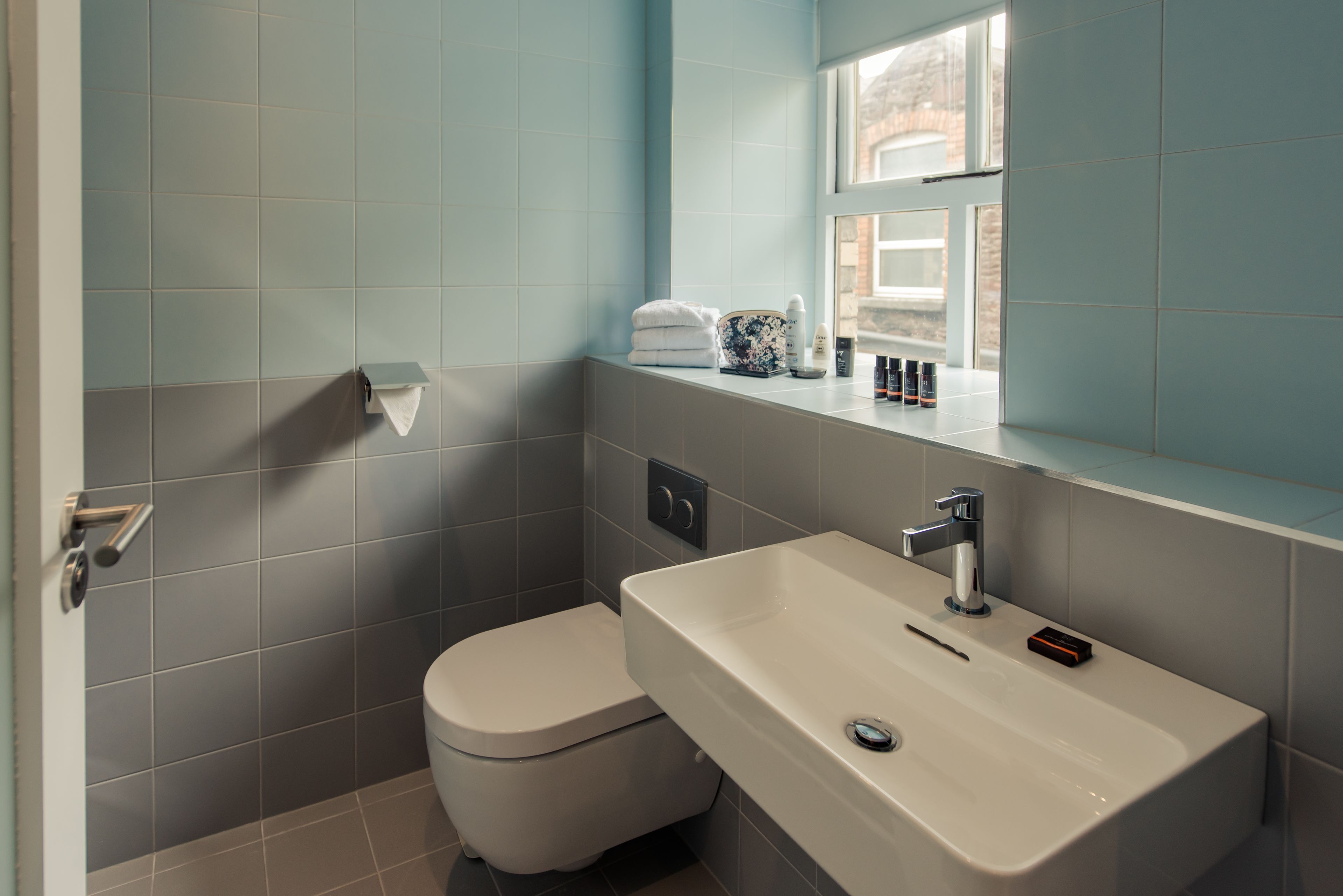 A bathroom with a toilet, sink, and window.