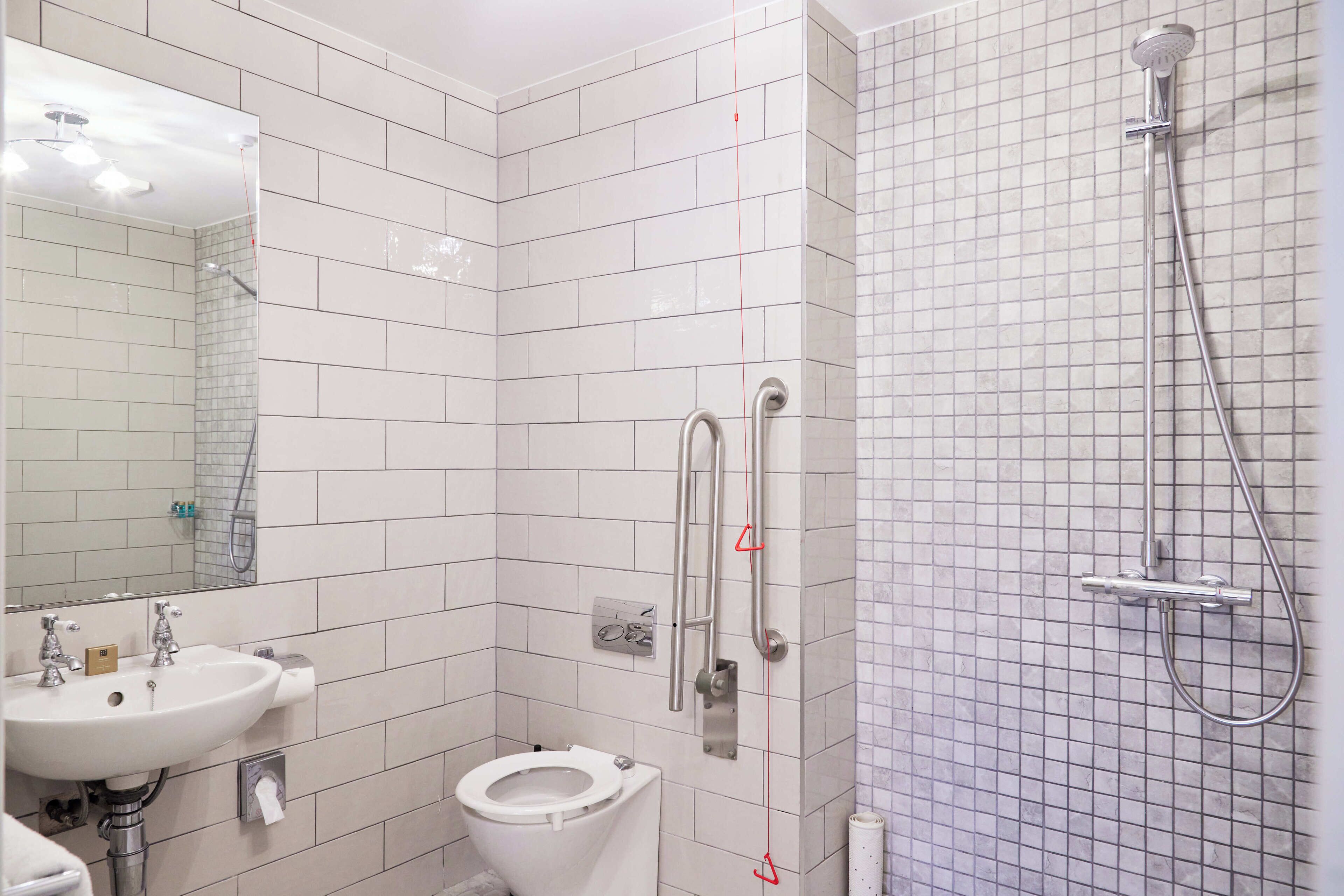 Un baño con lavamanos blanco, inodoro y ducha con cabezal de ducha de mano.
