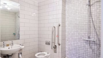 Un baño con lavamanos blanco, inodoro y ducha con cabezal de ducha de mano.
