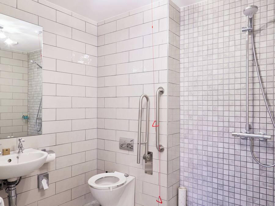 Un baño con lavamanos blanco, inodoro y ducha con cabezal de ducha de mano.