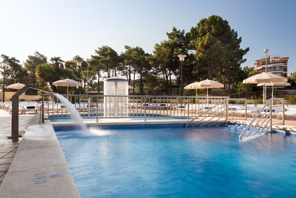 Una piscina cubierta, sombrillas, tumbonas