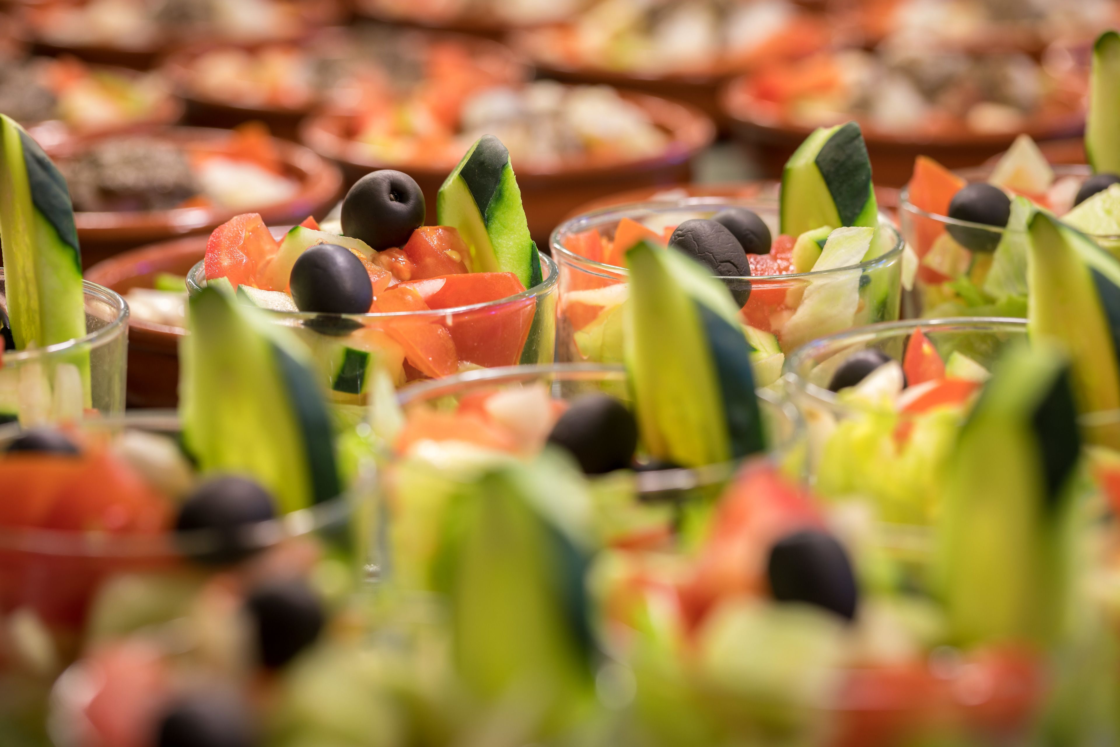 A buffet with various dishes including salads with cucumbers, tomatoes, and olives.