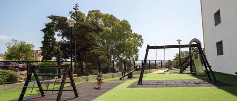 An outdoor playground with swings, a slide, and a climbing structure.