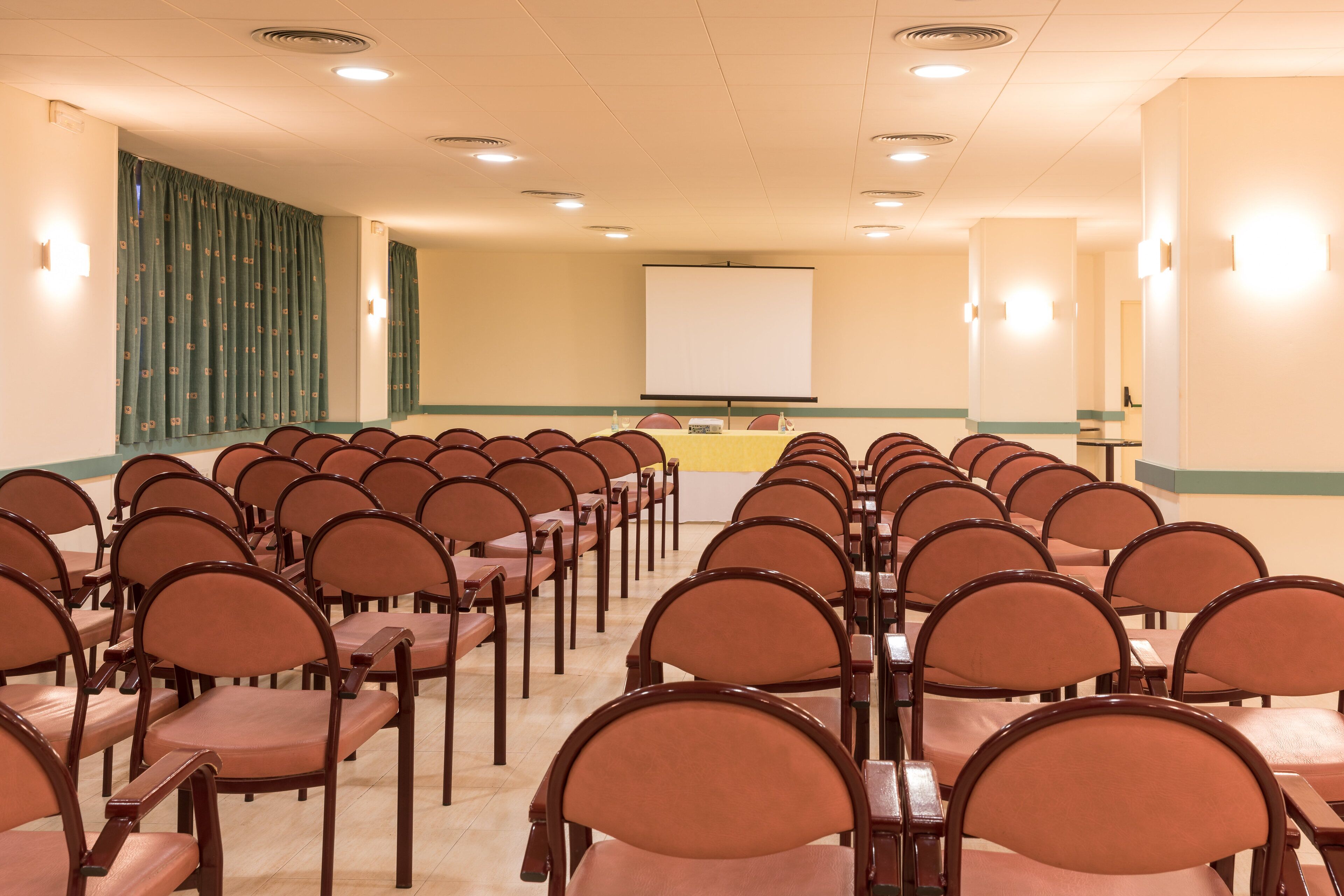 A conference room with rows of chairs and a projection screen.