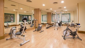 Un gimnasio con diversos equipos de ejercicio, como cintas de correr, bicicletas estáticas y máquinas de pesas.