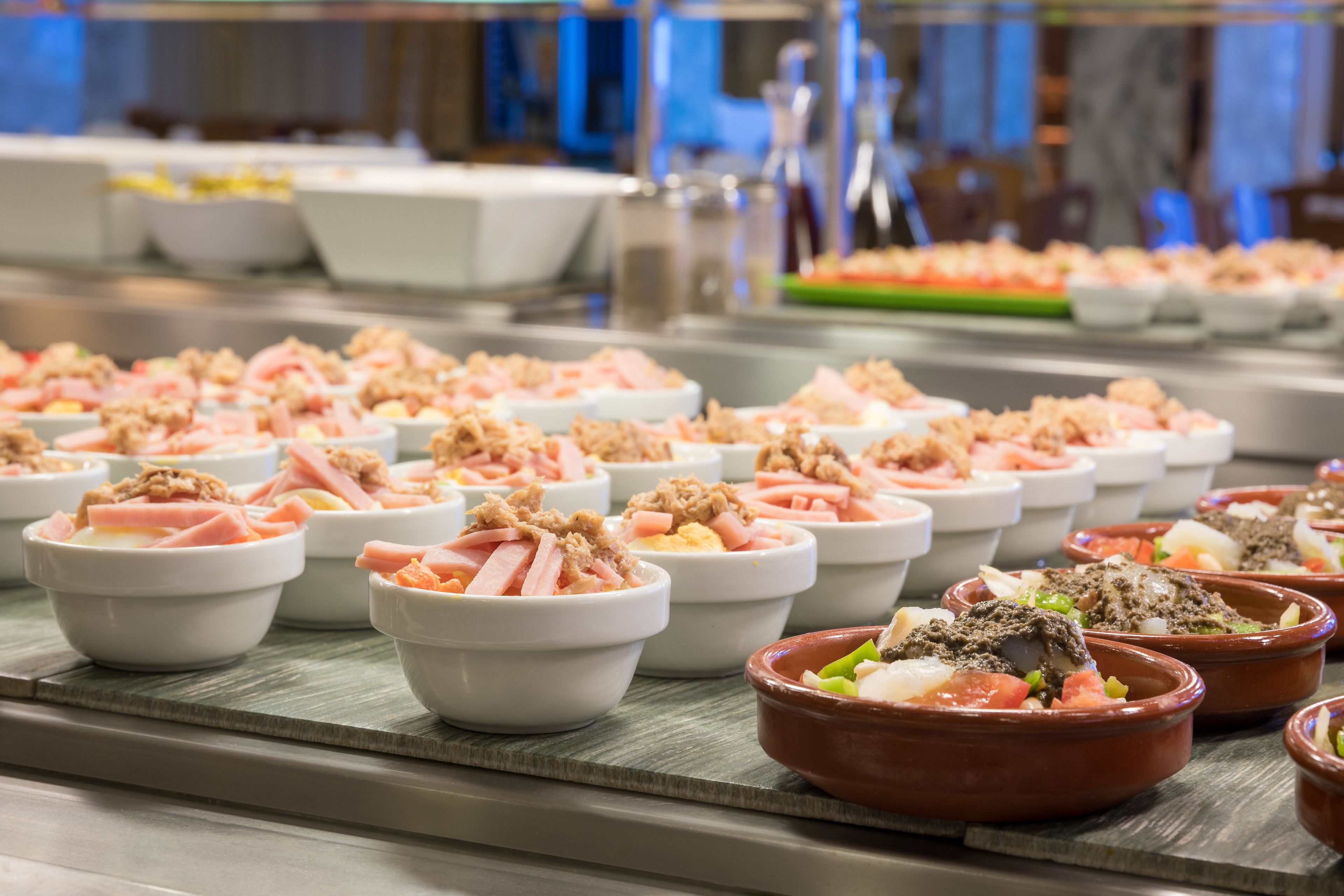 Un buffet proposant divers plats servis dans des bols et des plats en céramique, dont certains contiennent de la viande et des légumes.