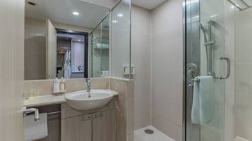 A modern bathroom with a glass shower enclosure, a sink, and a mirror.