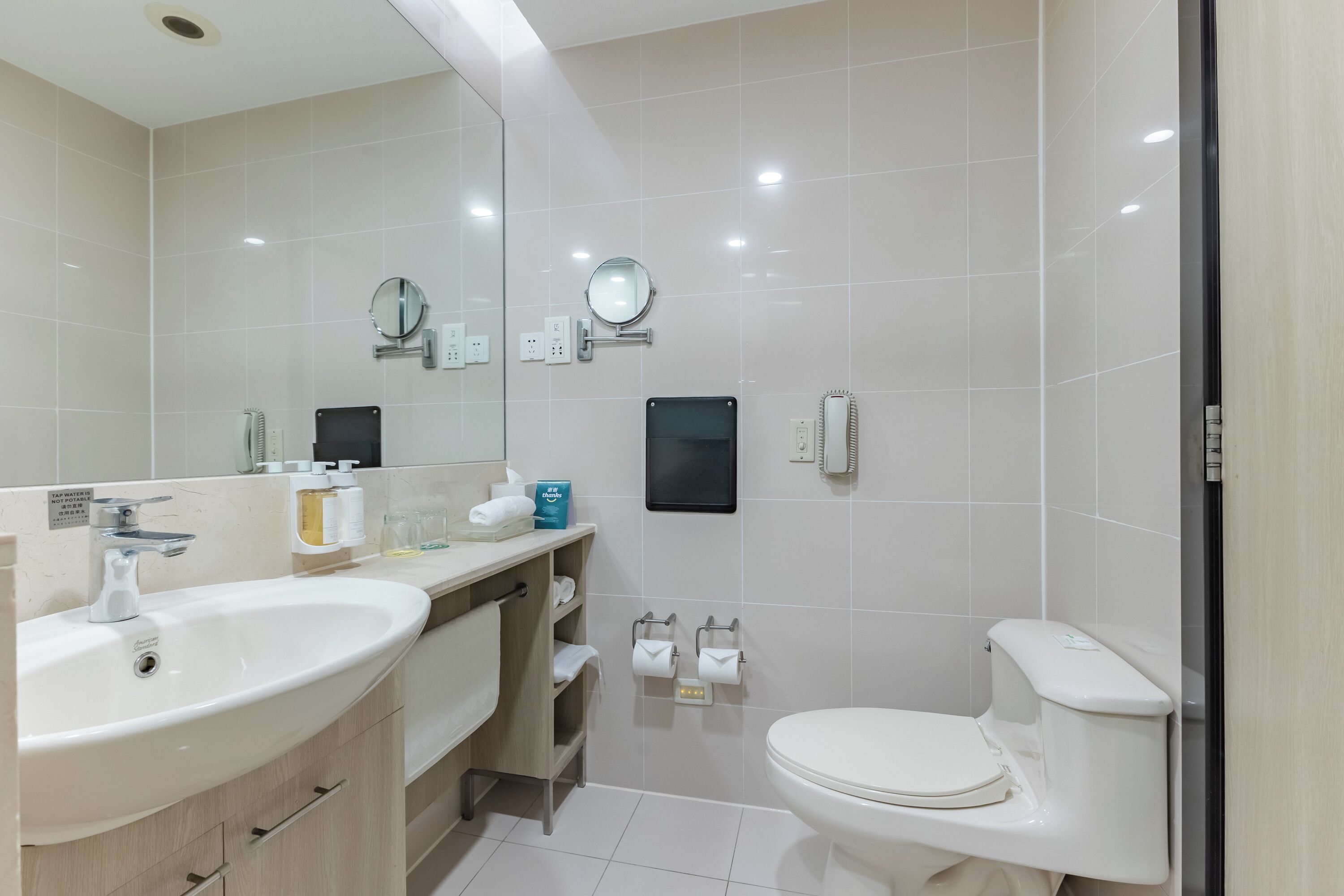 Een moderne badkamer met twee wastafels, een toilet en een douche.