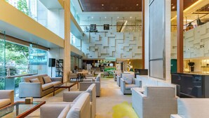 A spacious lobby with multiple seating areas, a central coffee station, and a view of the outdoors. - Holiday Inn Vista Shanghai by IHG (Shanghai)