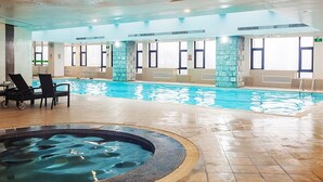 An indoor swimming pool with a hot tub, lounge chairs, and stone pillars. - Holiday Inn Vista Shanghai by IHG (Shanghai)