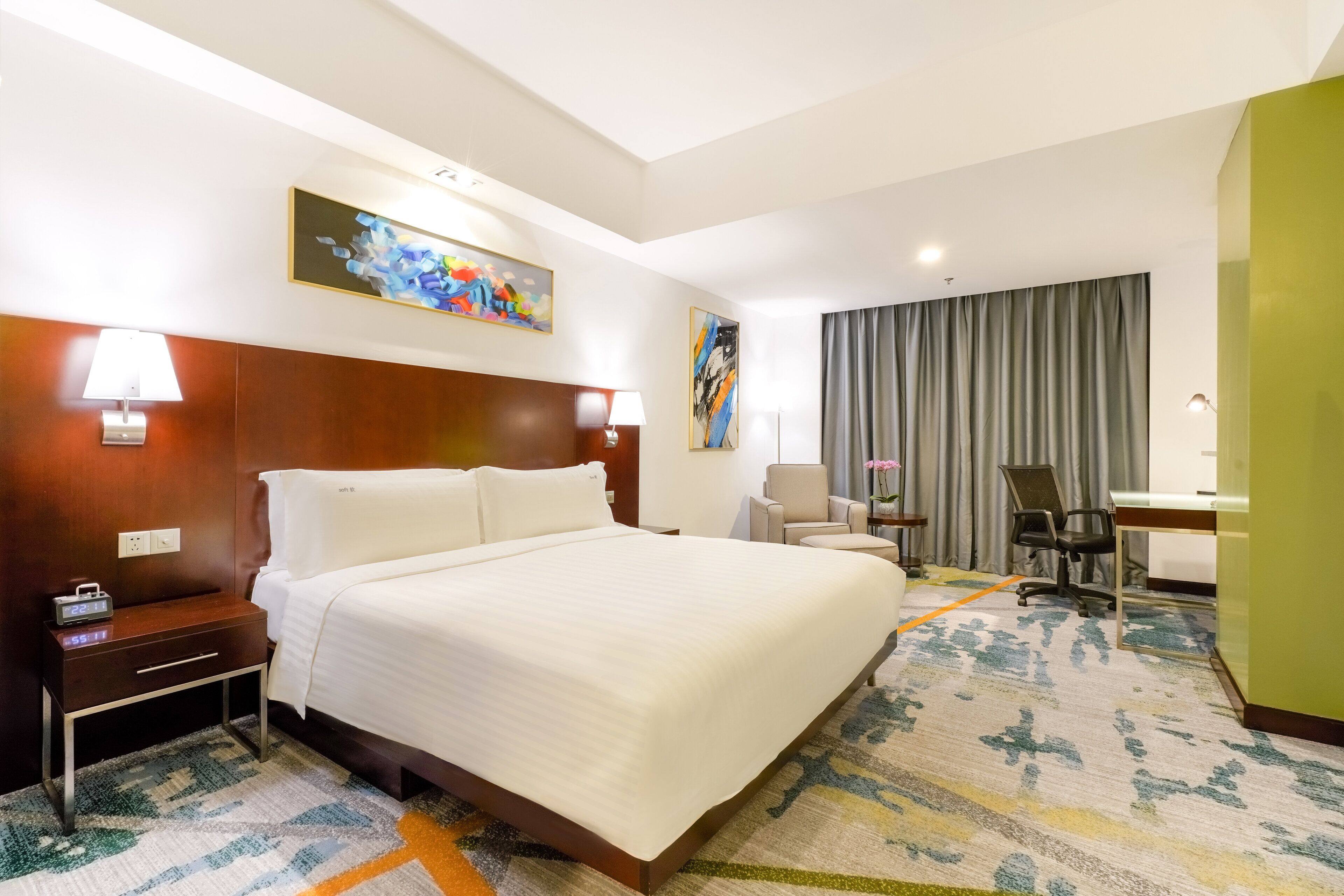 Ein Hotelzimmer mit einem großen Bett, Nachttischen, einem Schreibtisch und einem Stuhl.