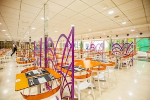 A spacious dining area with multiple tables and chairs, featuring a modern design with purple accents and a clean, well-lit environment.