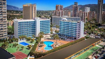 Ein Hotel mit mehreren Hochhäusern, einem Schwimmbad und einem Tennisplatz.