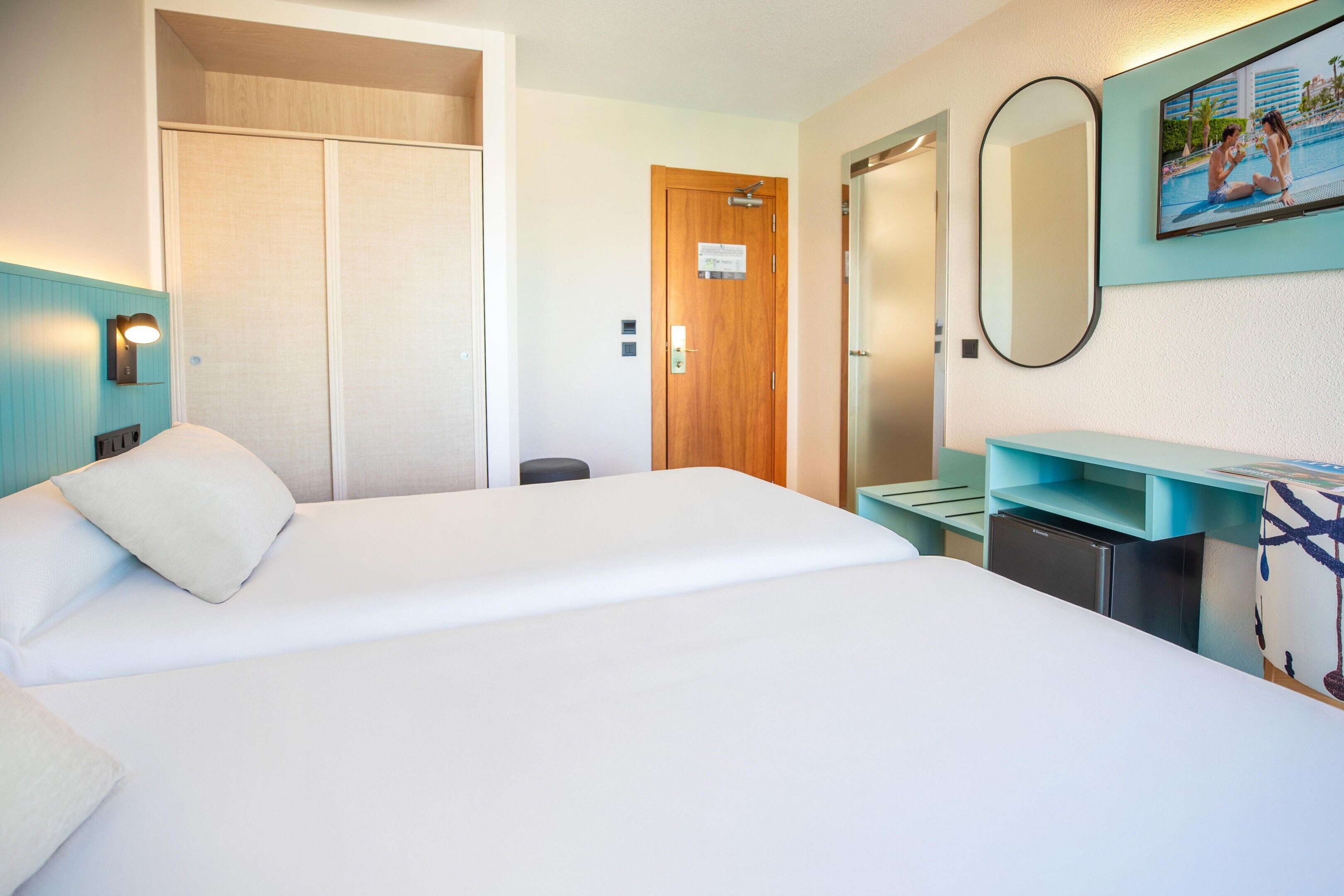 Ein Hotelzimmer mit Bett, Schreibtisch, Spiegel und Tür.