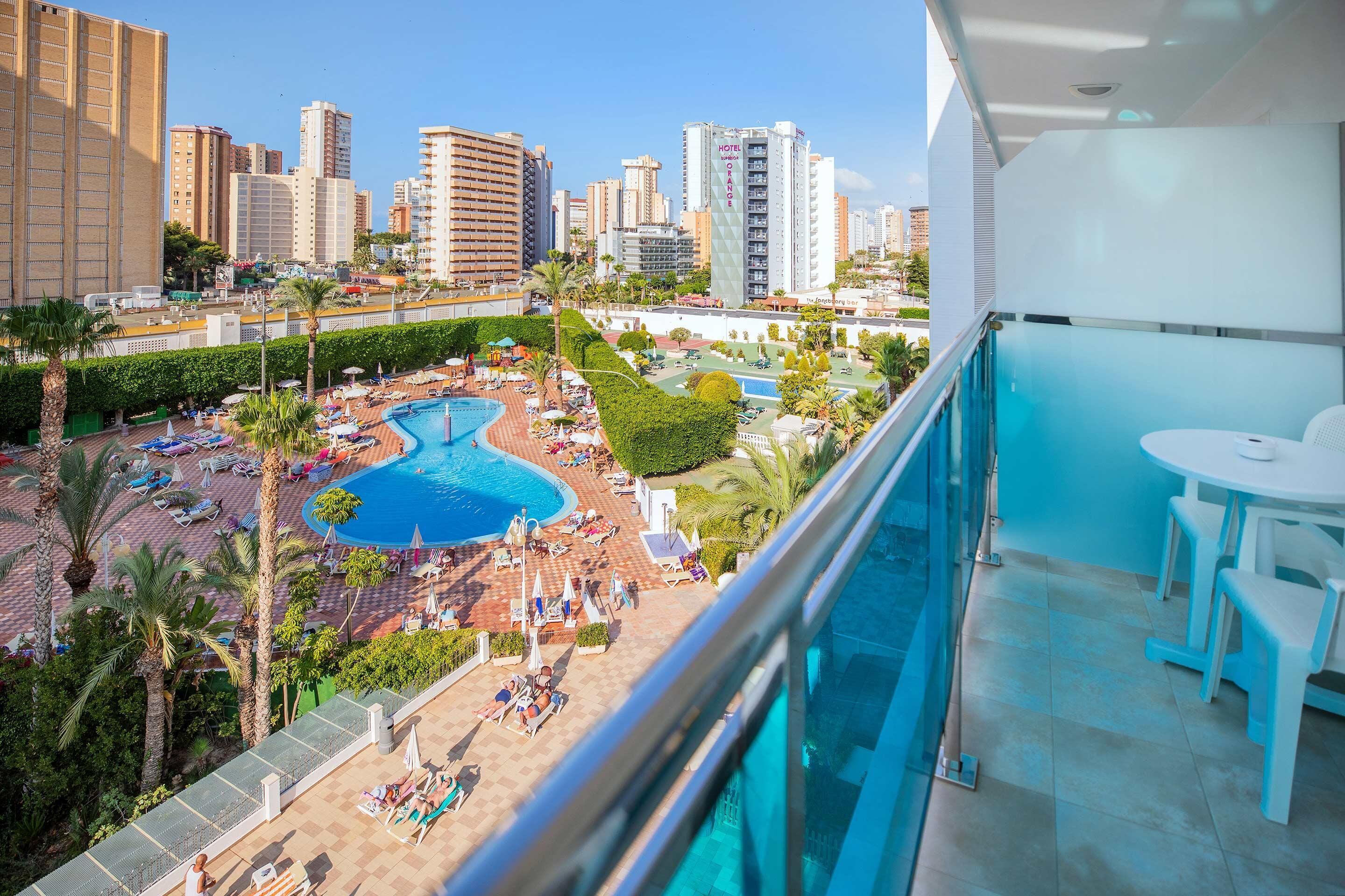 Balcón de hotel con vista a una piscina y al paisaje urbano.