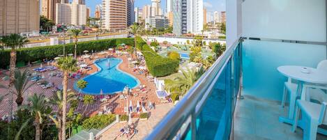 Balcón de hotel con vista a una piscina y al paisaje urbano.