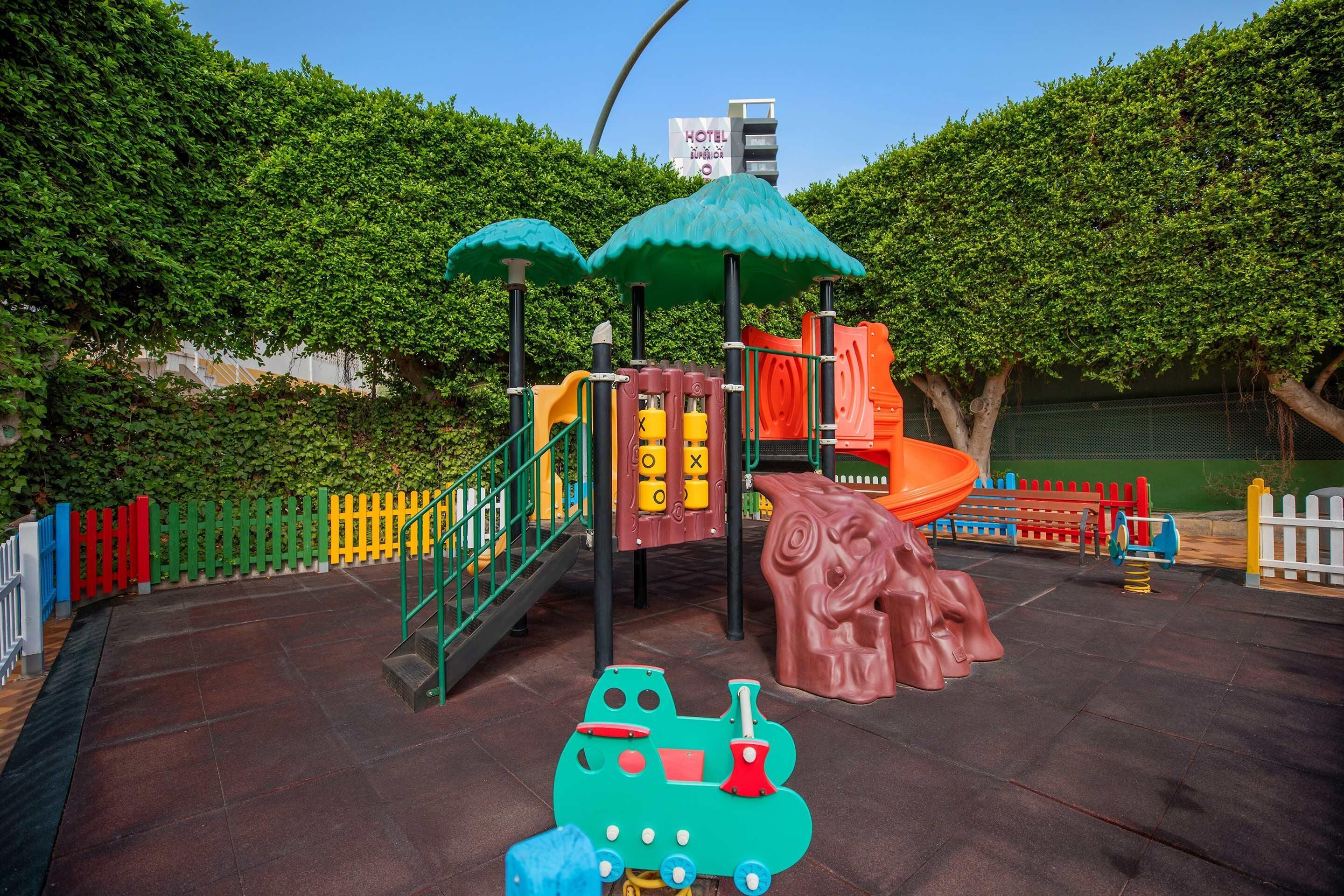 A playground with a slide, climbing structures, and a train ride.