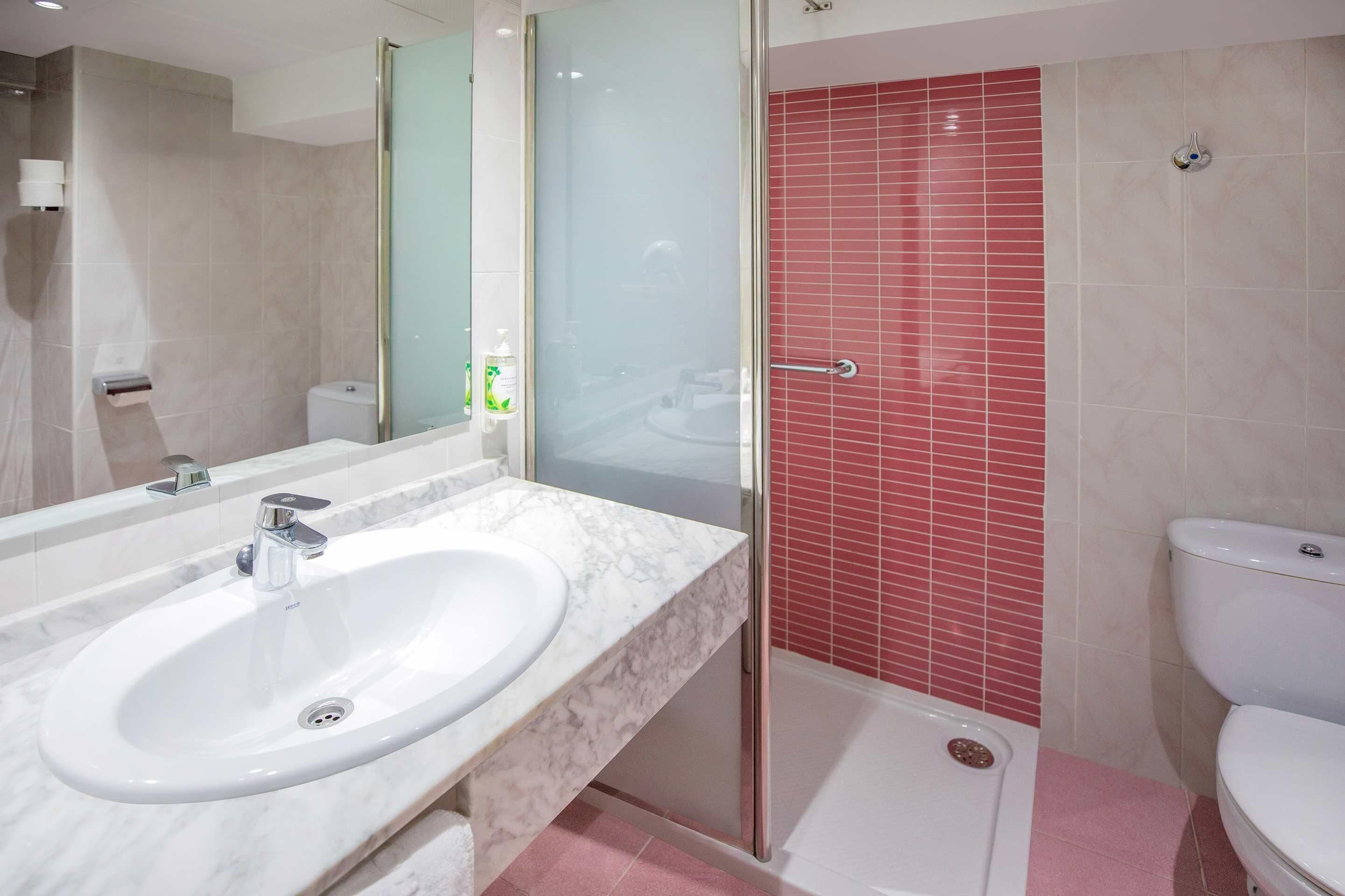 A modern bathroom with a marble sink, a glass-enclosed shower, and a toilet.