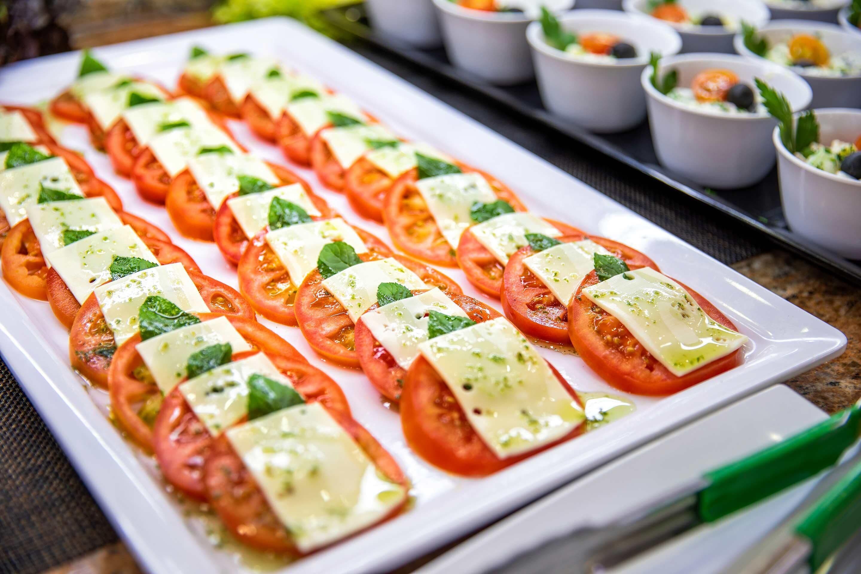 Un plateau de bouchées apéritives à base de tomates et de fromage.
